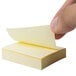 A hand holding a Universal yellow self-stick note.