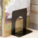 A black metal Universal steel bookend with a hole in the middle holding a book.