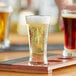A person pouring beer into an Acopa flared Pilsner beer tasting glass on a table.