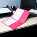 A hand holding a red Universal embossed paper pocket folder with papers inside on a white desk.