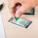 A hand using a Universal green page flag dispenser to mark a green piece of paper.