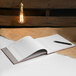 A Rediform burgundy visitor register book on a table with a pen.