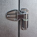 A metal hinge attached to the door of an outdoor walk-in freezer.
