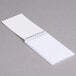 A white spiral bound notebook with lined paper on top.