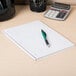 A pen on a Mead legal rule notebook on a table with a calculator.