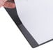 A hand using a Universal black economy view binder to hold paper.