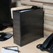 A black Universal economy view binder on a desk with papers inside.