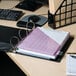 A close-up of a Universal black economy view binder on a table with a piece of paper and a pen.