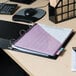 A black Universal economy non-stick view binder on a desk with a laptop, pen, and paper.