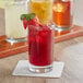 A tray with three Acopa Straight Up juice glasses filled with red liquid and ice, with strawberries on top.