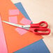 A Universal 3-pack of stainless steel scissors with red bent handles on a table.