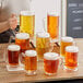 A woman holding an Acopa dimple beer mug filled with beer on a table in a brewery tasting room.