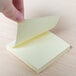 A hand holding a Universal yellow self-stick note.