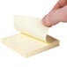 A finger holding a Universal yellow self-stick note.