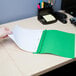 A hand holding a green Universal Office leatherette report cover with white paper inside.