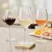 Three Acopa Select Blanc wine glasses on a table with wine and food.