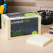 A white Universal yellow sticky note pad on a table.