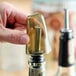 A translucent universal liquor pourer cover being placed on a bottle.