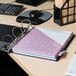 A Universal black non-view binder on a desk with pink paper inside.