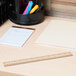 A Universal wood ruler on a desk with a notebook and pencils.