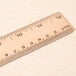 A Universal wooden ruler with metal edges on a wood surface.