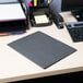 A black Universal 2-pocket paper folder on a desk with a computer and file.