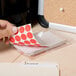 A person holding a red Universal round label.