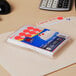A pack of Avery neon red round labels in a plastic package on a stack of paper on a desk.