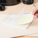 A person holding a stack of white rectangular file folder labels.