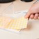 A hand putting an orange Avery color coding label on a piece of paper.