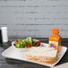 A white Huhtamaki Chinet rectangular paper food tray with a sandwich and salad on it.