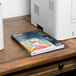 A box of Epson photo paper on a table next to a printer.
