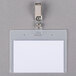 A white Universal Deluxe clip-on badge holder on a piece of paper.