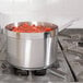 A Vollrath stainless steel sauce pan with red sauce cooking on a stove.