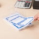 A person using a Universal white name badge with a blue border to write on.