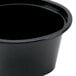 A white background with a Pactiv black oval plastic souffle container.
