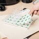 A hand putting a white round sticker on a plastic container.