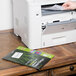 A hand putting an Avery Ecofriendly White Name Badge Label into a printer.