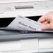 A person putting an Avery Ecofriendly White Adhesive Name Badge Label into a printer.