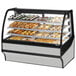 A True curved glass stainless steel dry bakery display case on a counter with trays of pastries.