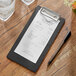 A black wood Choice menu holder with a receipt on a table.