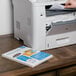 A hand putting a sheet of Avery rectangular white address labels into a printer.