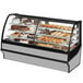 A True curved glass stainless steel dual service refrigerated bakery display case full of cakes and pastries.