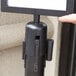 A hand using a black Lancaster Table & Seating sign frame on a black metal stanchion pole.