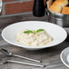 A bowl of pasta on a table with a spoon and fork.