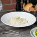 A bowl of pasta on a table with a fork and knife