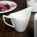 A white Royal Rideau porcelain creamer on a table.