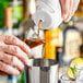 A person pouring Real Blue Agave Nectar into a cup.