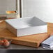 An Ateco square aluminum cake pan on a cutting board.