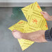 A man using a yellow Spilfyter absorbent pad to clean up a spill on the floor in a restaurant.